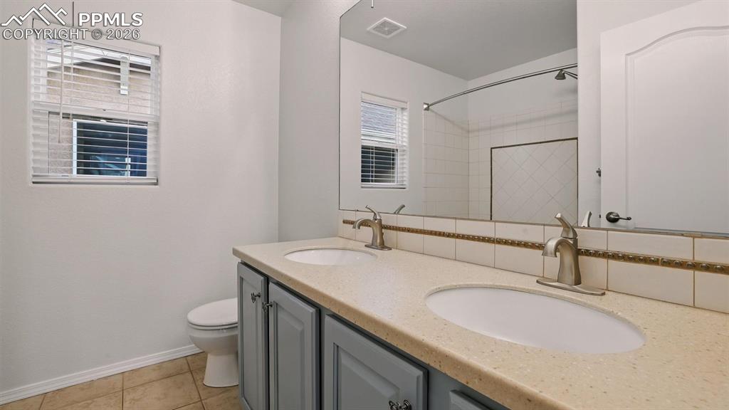 Upper Level Full Hall Bathroom with dual sink vanity, mirror, and tiled tub/shower.