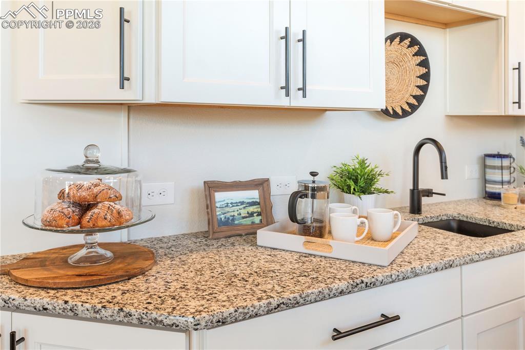 Kitchen view of light stone counters and white cabinets
