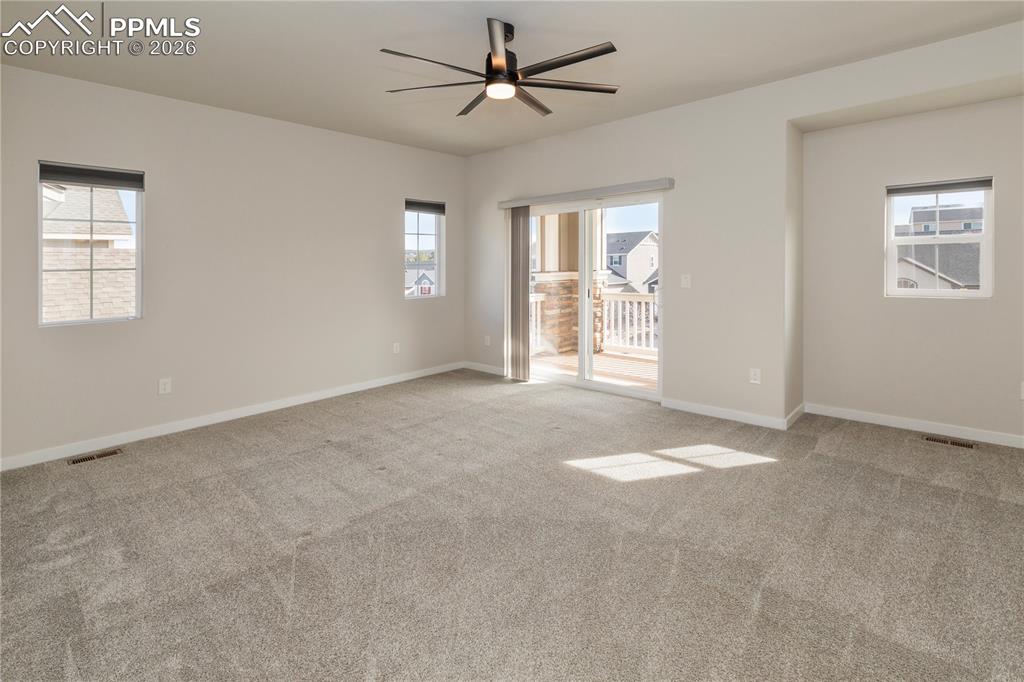 Spacious primary retreat with plenty of natural light, a covered balcony and ceiling fan.