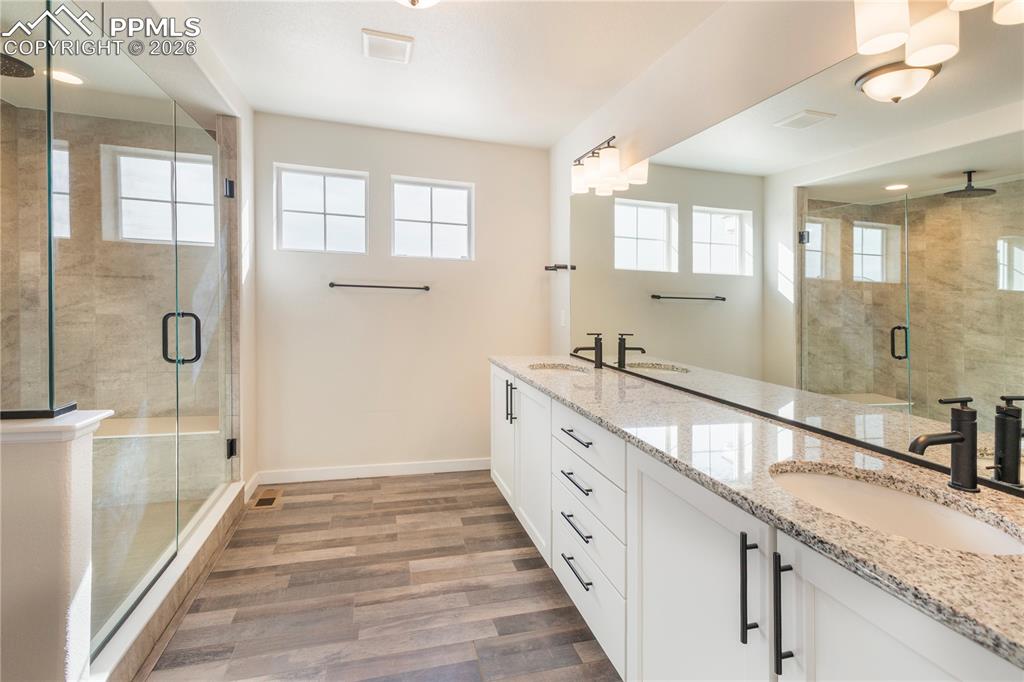 Light and bright ensuite with granite double vanity, spa shower, healthy amount of natural light, and LVP flooring.