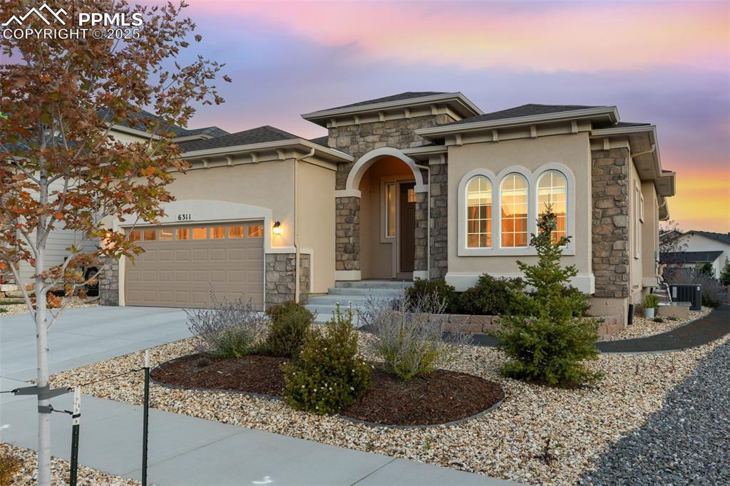 Mediterranean / spanish house with stone siding, concrete driveway, and stucco siding