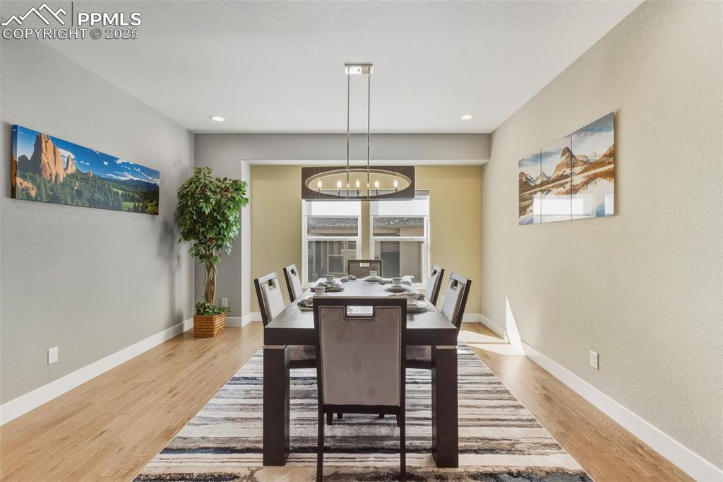 Dining area with light wood-style flooring, a chandelier, recessed lighting, and a textured wall