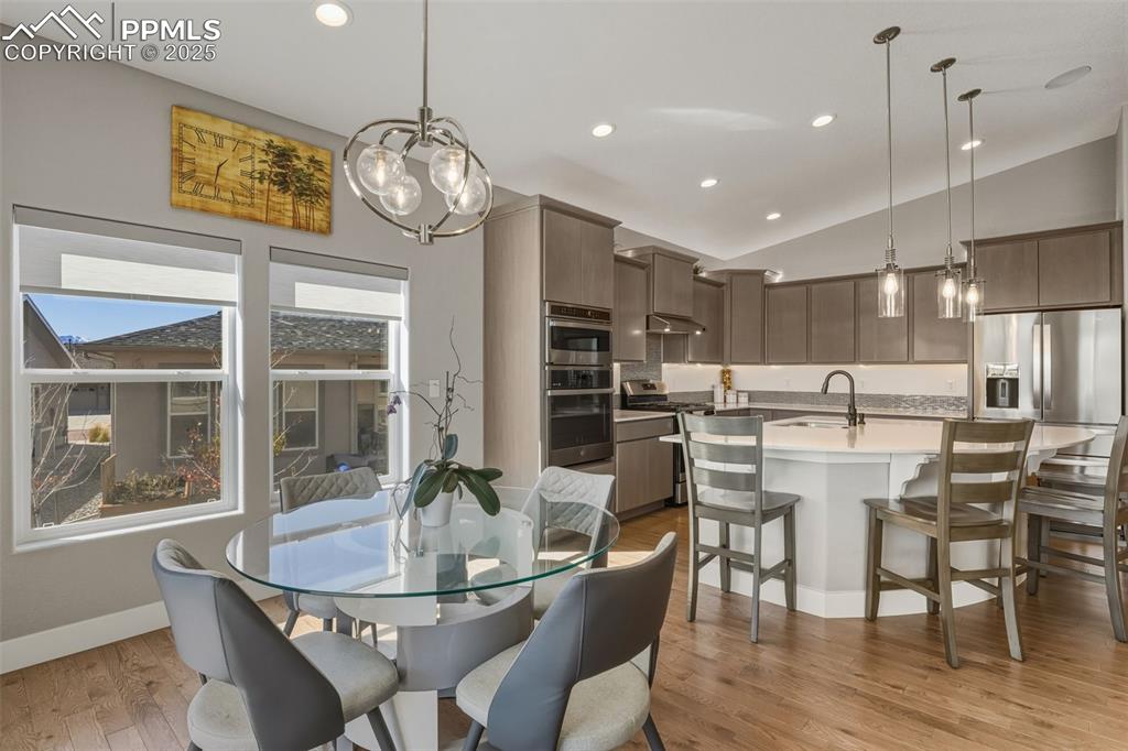 Dining room featuring light wood-style floors, vaulted ceiling, recessed lighting, and a chandelier