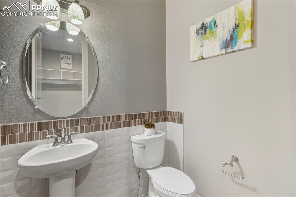 Bathroom with tile walls, a textured wall, and a wainscoted wall