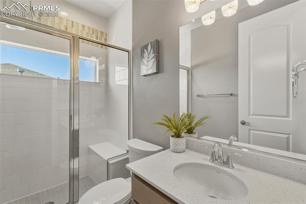 Full bath with vanity, a shower stall, and a textured wall
