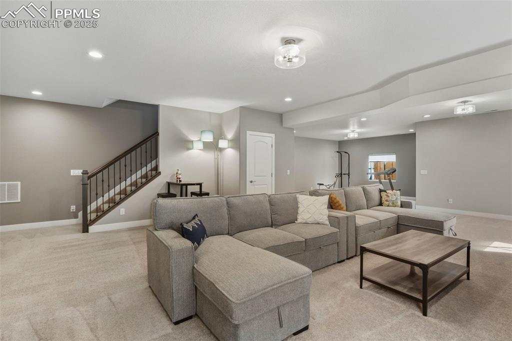 Living area with recessed lighting, light carpet, and stairs
