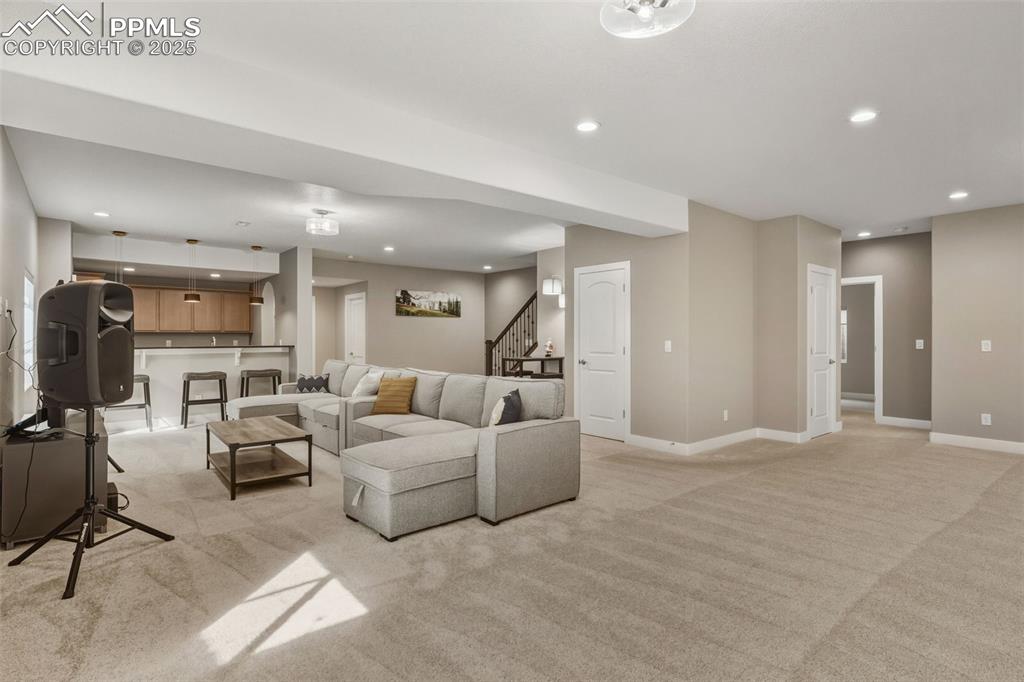 Living area featuring recessed lighting, light colored carpet, and stairs