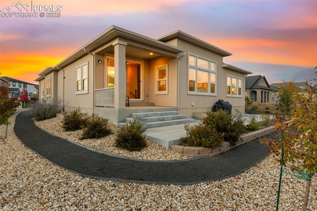 Back of property at dusk featuring stucco siding and a porch