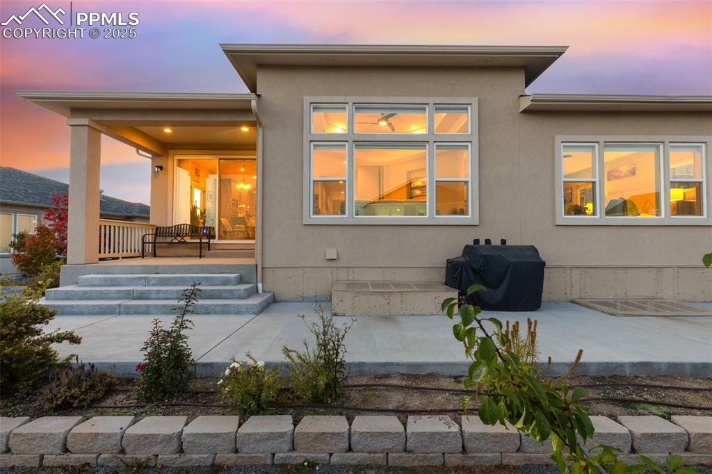 Back of house at dusk with stucco siding and a patio