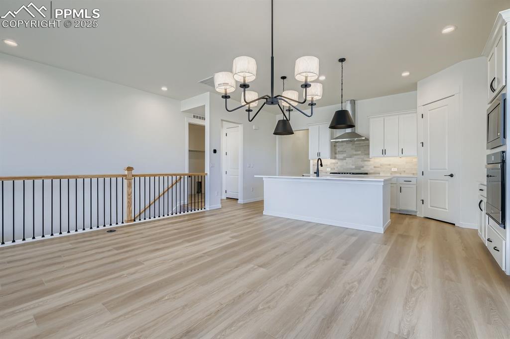 Kitchen with decorative backsplash, hanging light fixtures, white cabinets, open floor plan, and recessed lighting