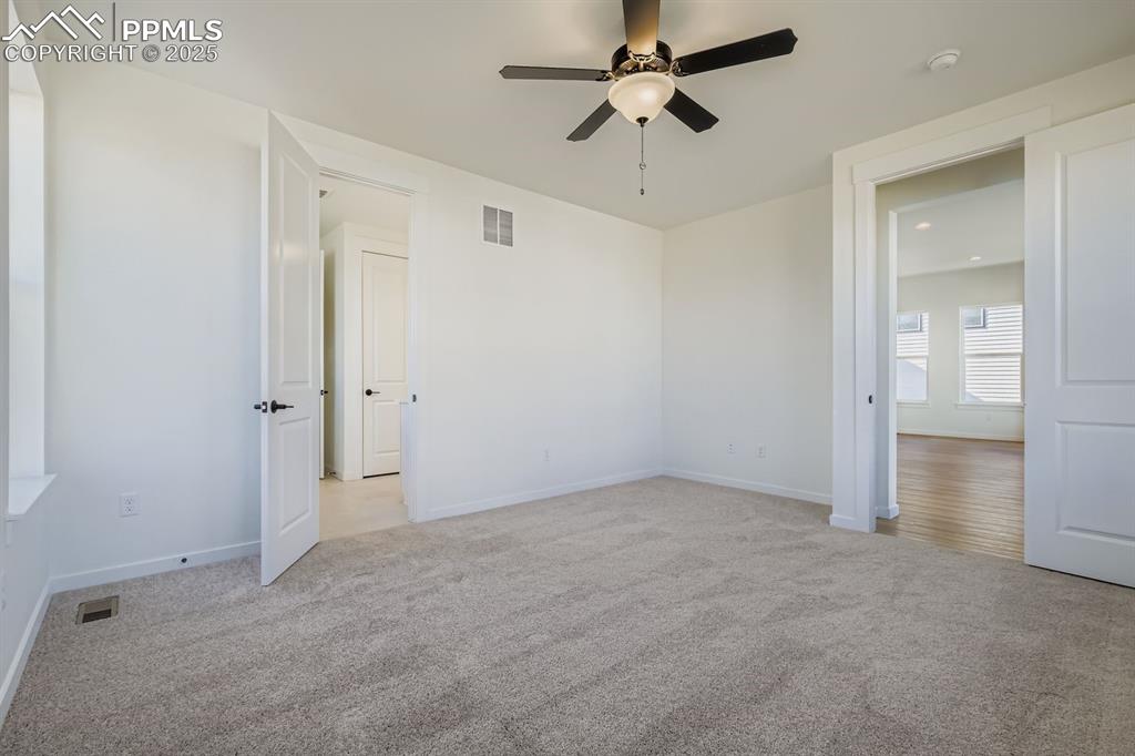 Unfurnished bedroom featuring light carpet and a ceiling fan
