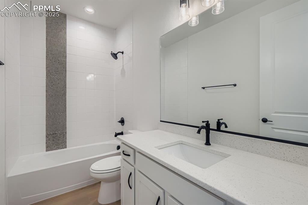 Bathroom featuring vanity, tub / shower combination, light wood-style floors, and recessed lighting