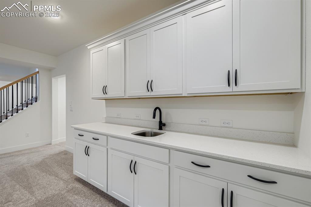 Kitchen featuring white cabinetry, light carpet, light stone counters, and recessed lighting
