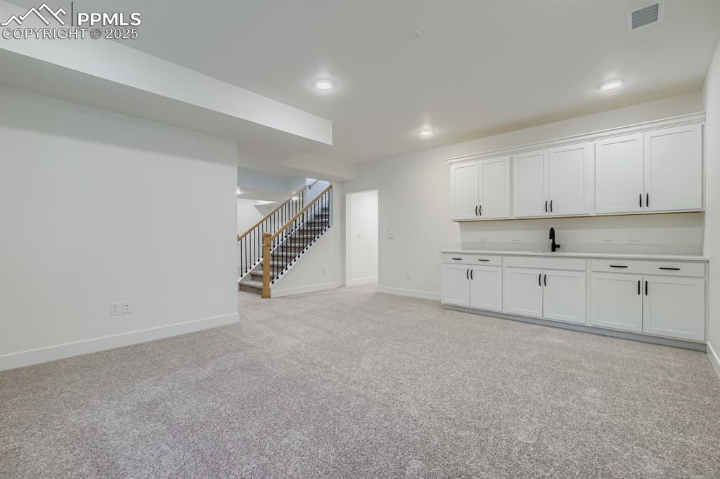 Basement with stairway, light carpet, and recessed lighting