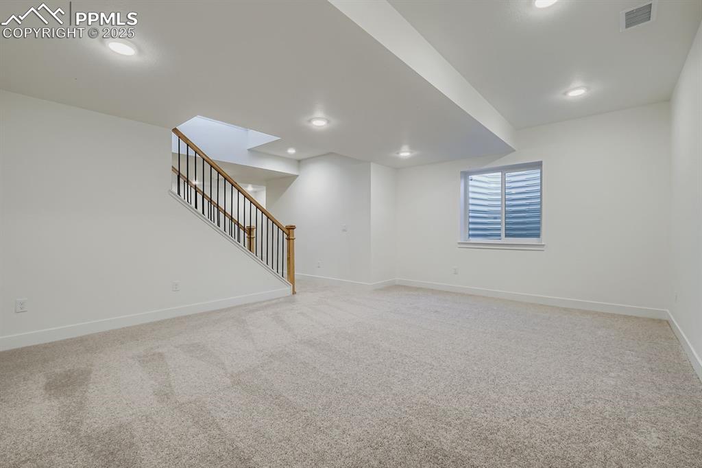 Basement with light carpet, stairs, and recessed lighting