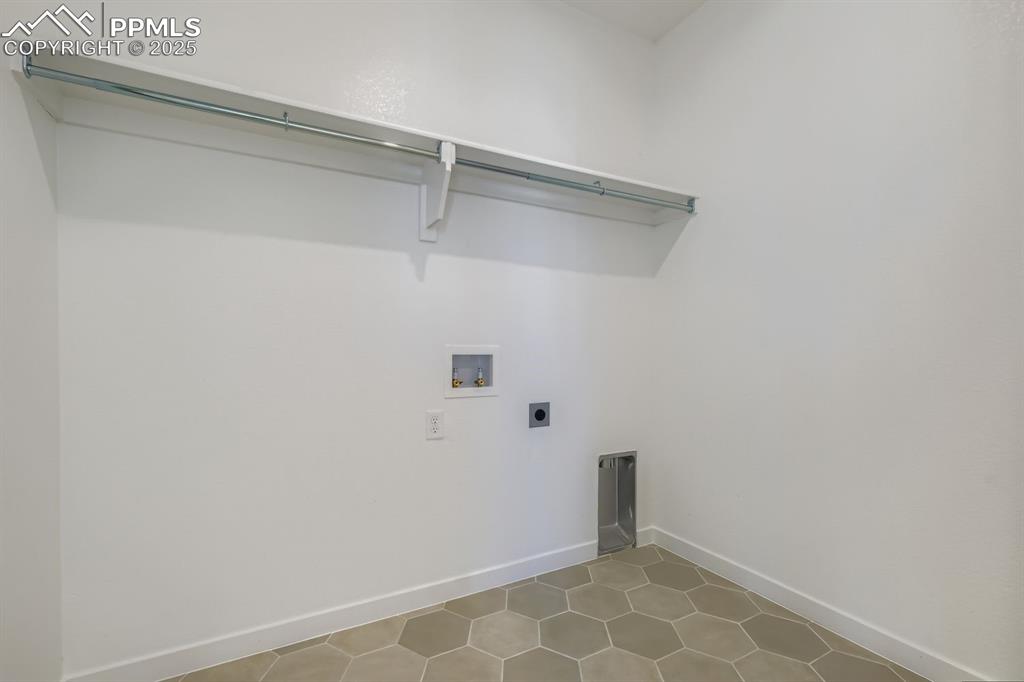 Washroom with hookup for an electric dryer, hookup for a washing machine, and tile patterned floors