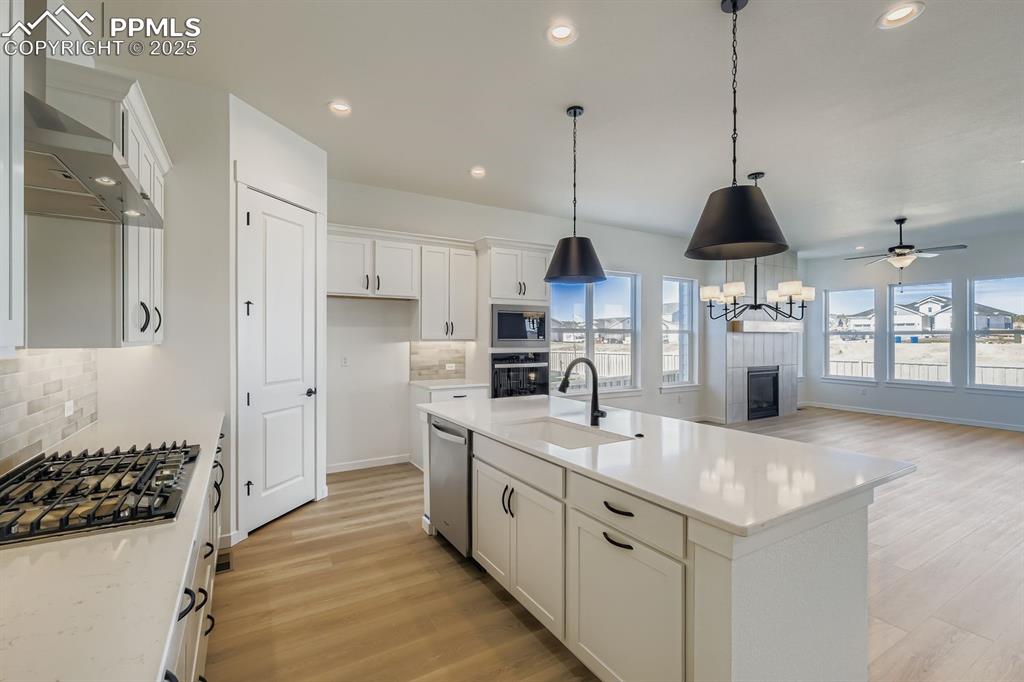 Kitchen featuring backsplash, light wood-type flooring, white cabinets, recessed lighting, and decorative light fixtures