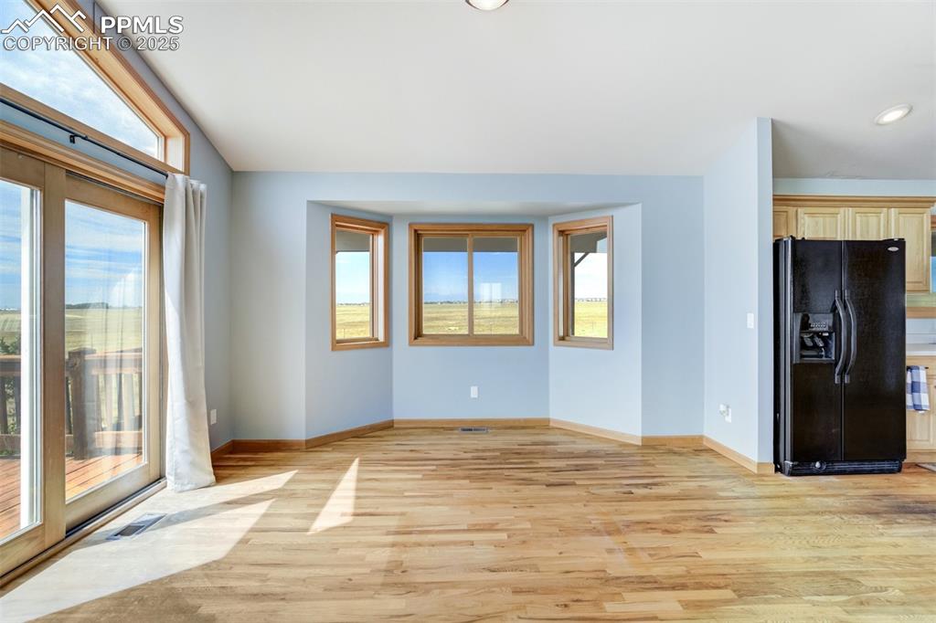 Unfurnished living room featuring light wood-type flooring and baseboards