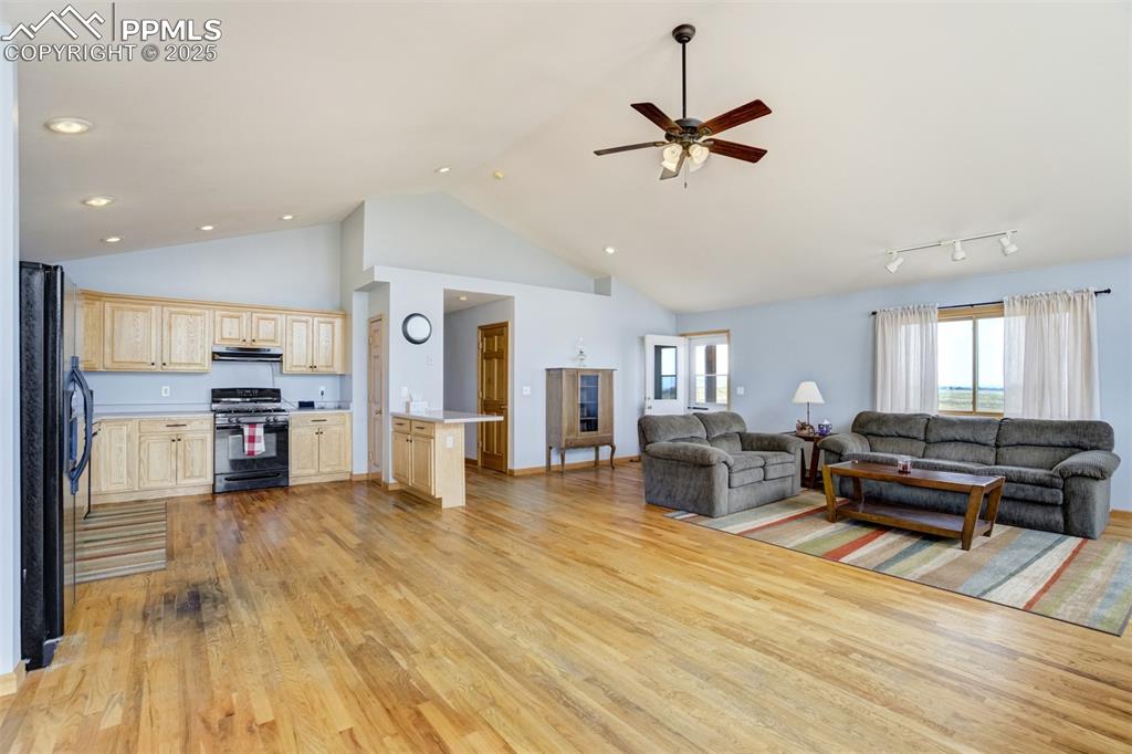 Living room with high vaulted ceiling, light wood finished floors, and a ceiling fan