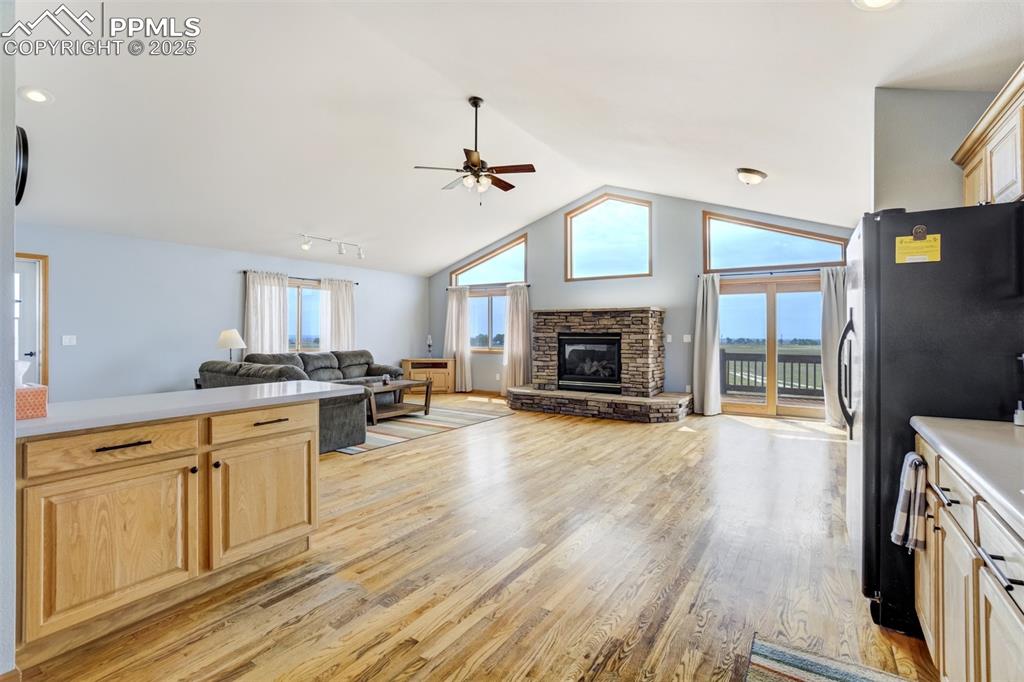 Kitchen featuring light brown cabinets, open floor plan, light wood-type flooring, lofted ceiling, and recessed lighting