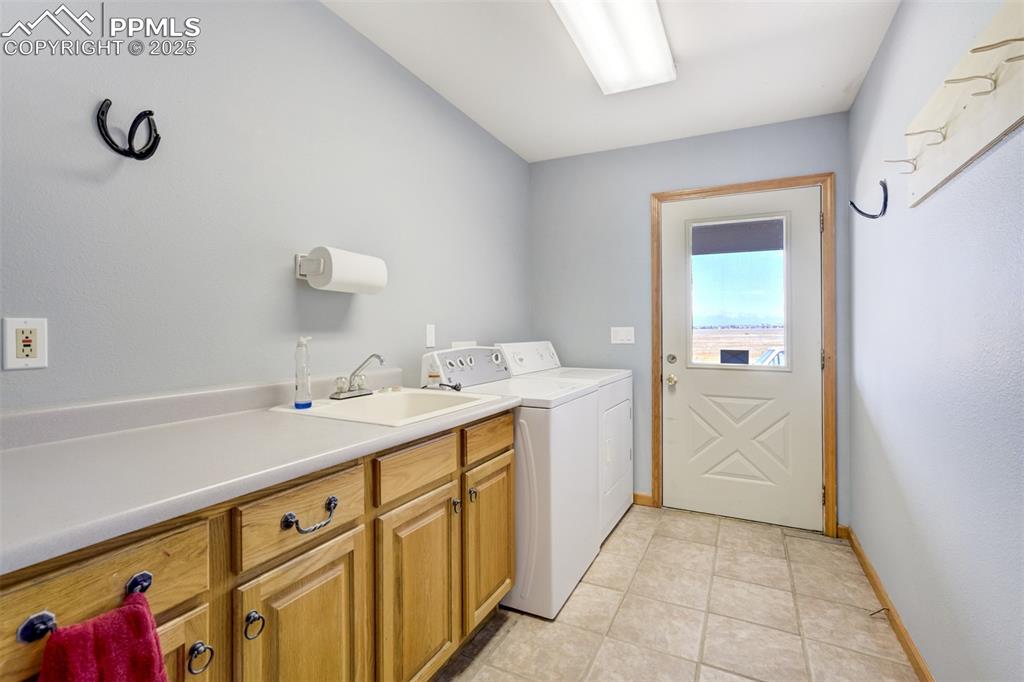 Laundry area with independent washer and dryer, cabinet space, and light tile patterned flooring