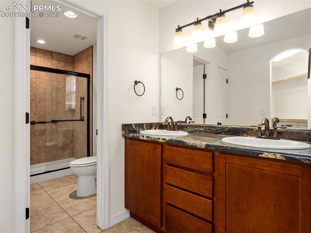 Primary Bathroom featuring a shower stall, double vanity, and tile patterned floors
