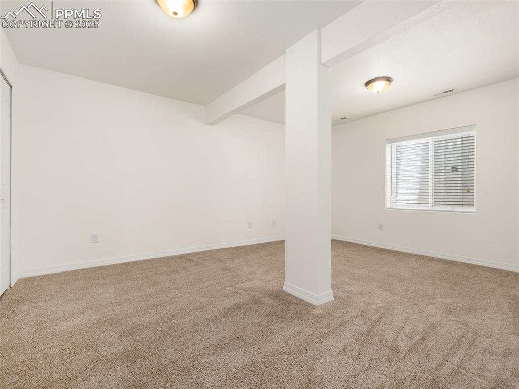 Spare room with light colored carpet and beam ceiling