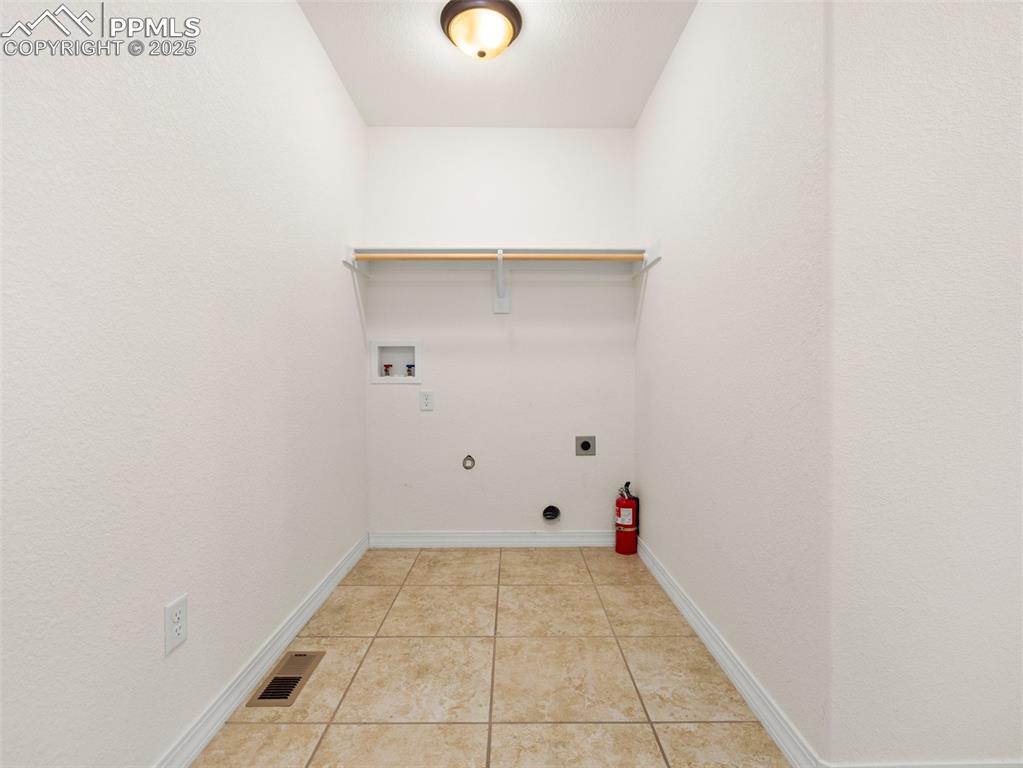 Laundry room featuring hookup for a gas dryer, washer hookup, light tile patterned flooring, and electric dryer hookup