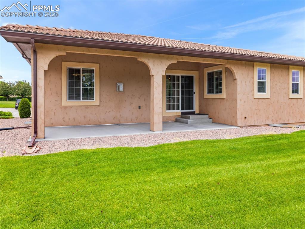Rear view of house featuring a yard, stucco siding, and a patio