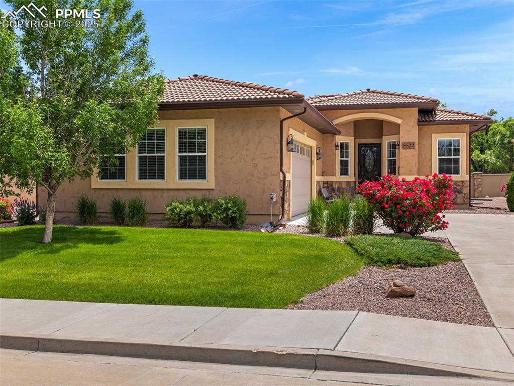 Mediterranean / spanish-style house with a garage, a front yard, stucco siding, and a tile roof