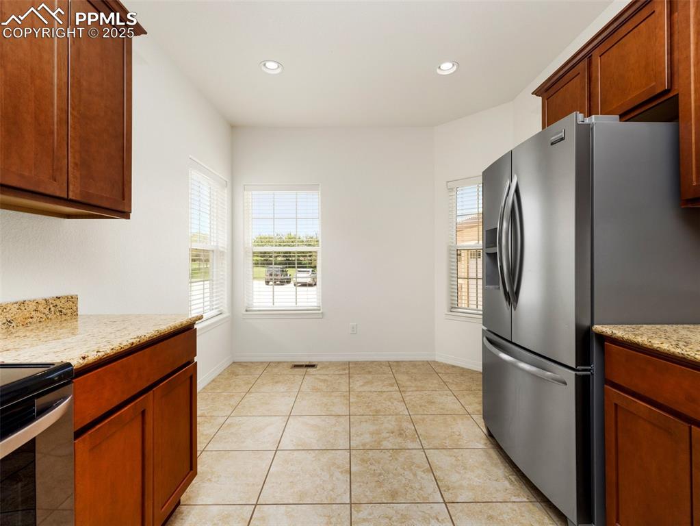 Kitchen featuring appliances with stainless steel finishes, recessed lighting, light tile patterned floors, and light stone countertops