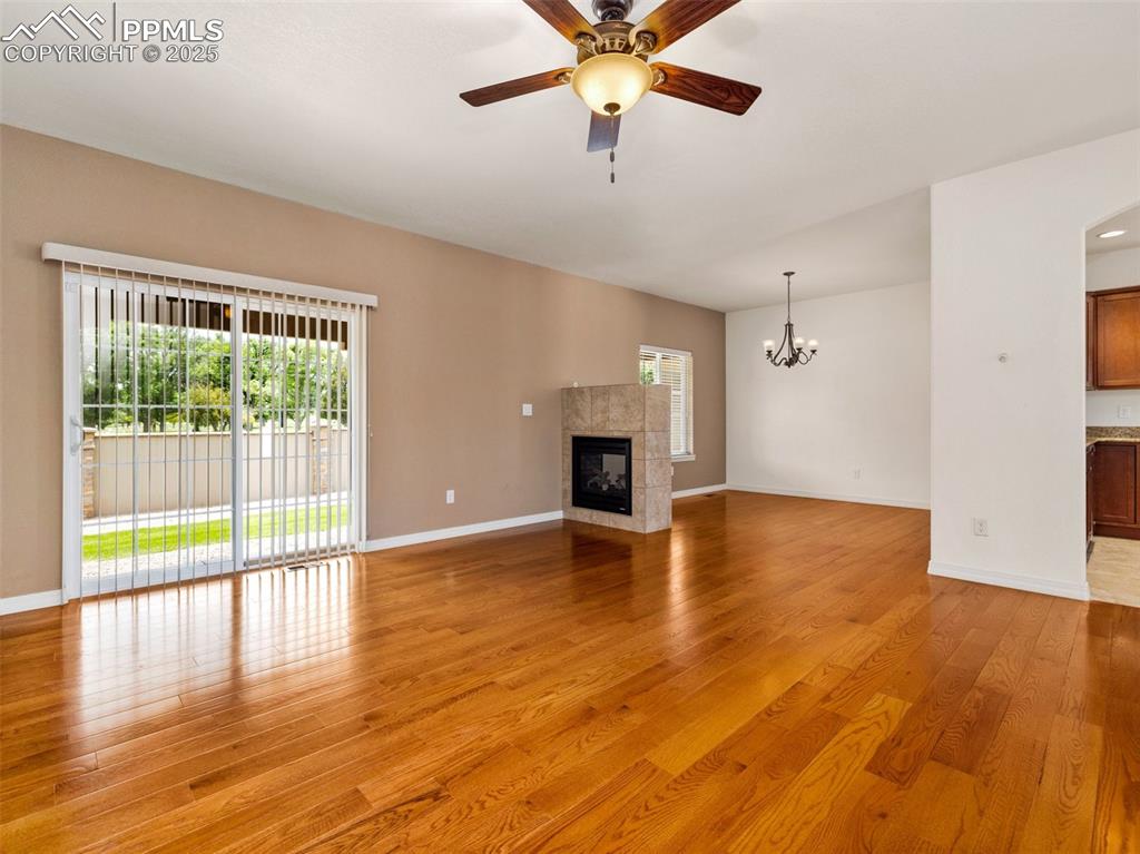 Unfurnished living room with light wood finished floors, a fireplace, a ceiling fan, and a chandelier