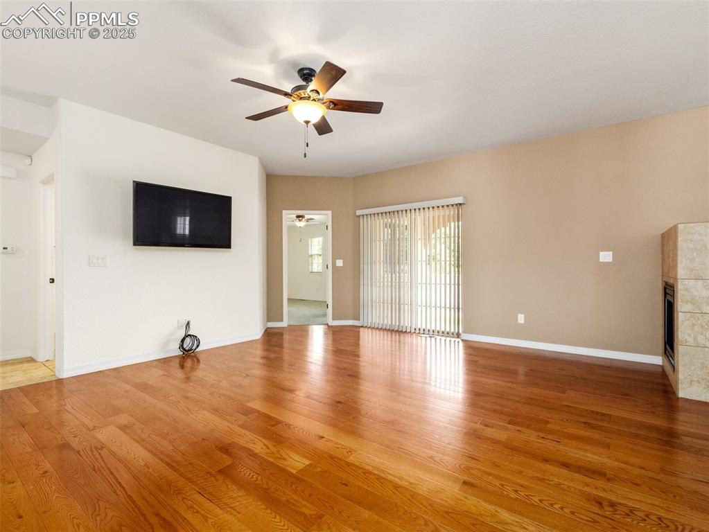 Unfurnished living room featuring ceiling fan, a fireplace, and light wood-style flooring
