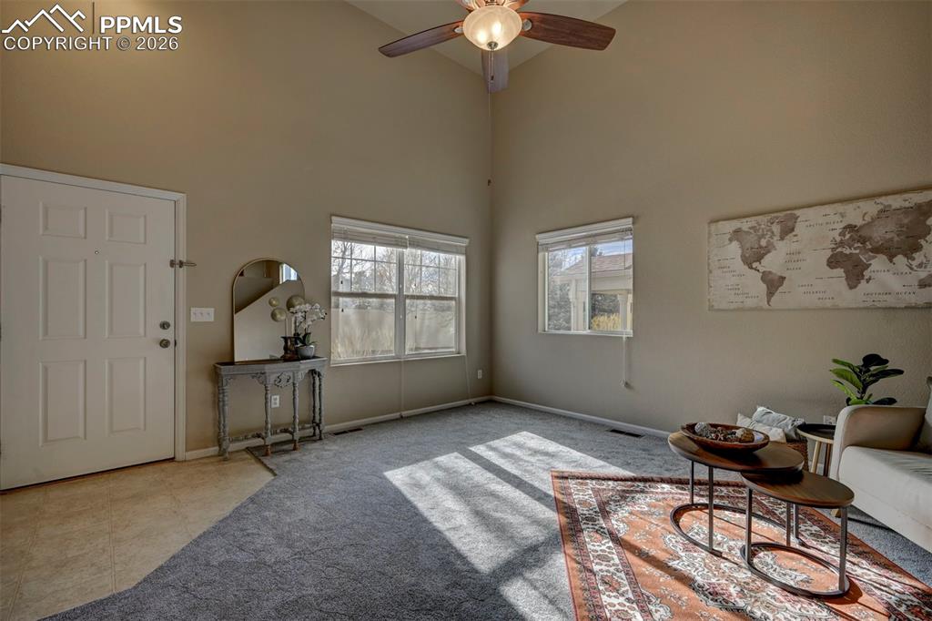 Beautiful entryway into the living room with new carpet, high ceilings, and fan.