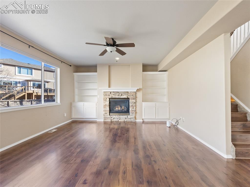 Unfurnished living room with dark wood-style floors, a ceiling fan, and a fireplace