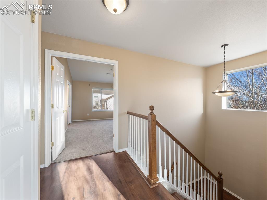 Corridor featuring dark wood-style flooring and an upstairs landing