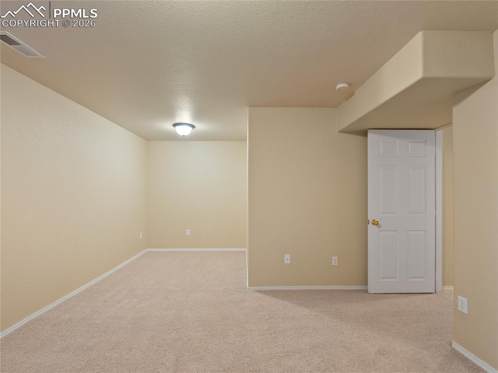 Finished basement  bedroom featuring light colored carpet and a textured ceiling