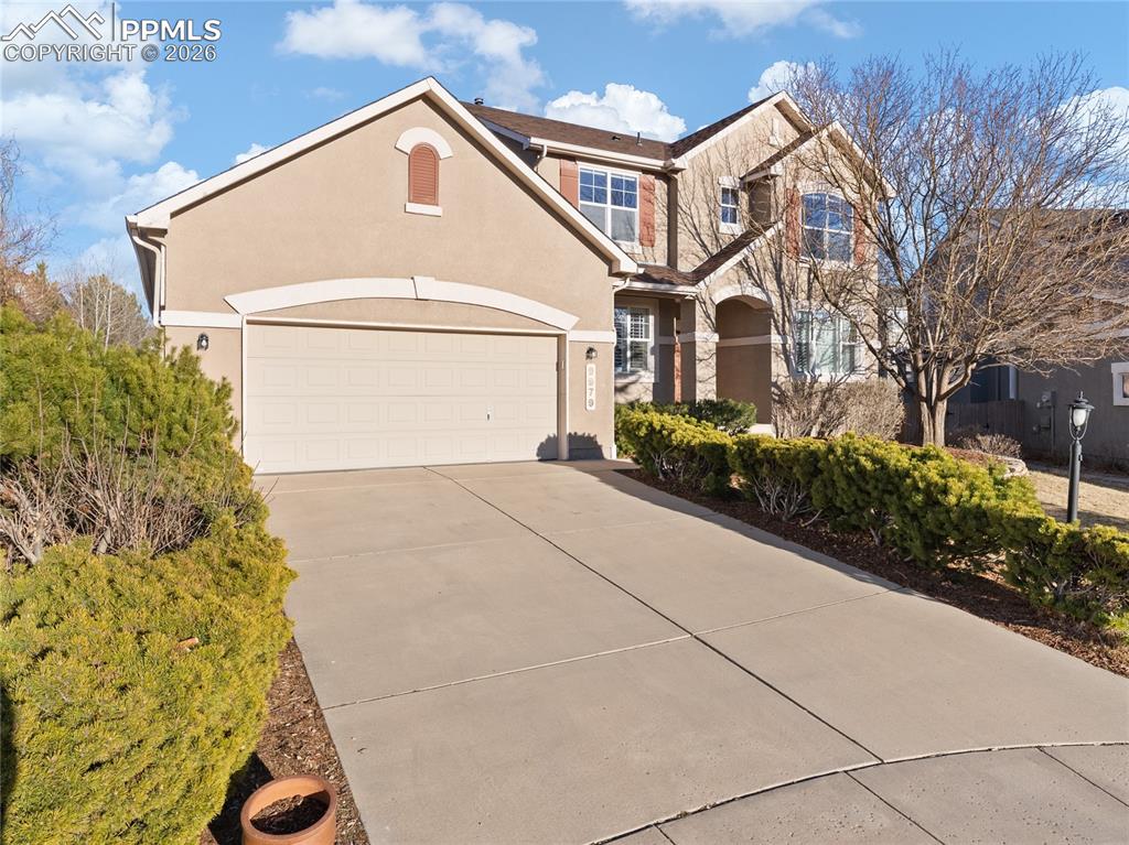 View of front of property with concrete driveway, stucco siding, an attached garage, and stone siding