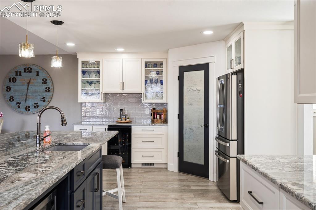 Two sinks in this well thought out kitchen and includes a separate wine bar area with wine fridge and glass front cabinets. Lovely glass pantry door too!
