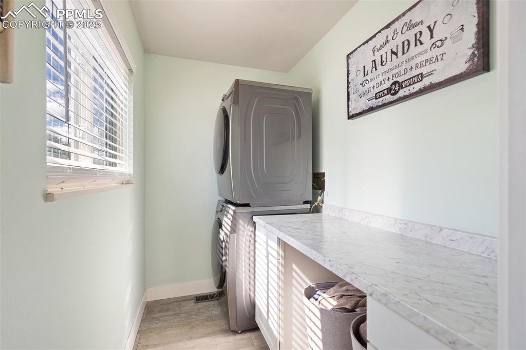 Airy main level laundry room off the kitchen, perfect for a stackable washer/dryer with built in folding counter and cabinet space.