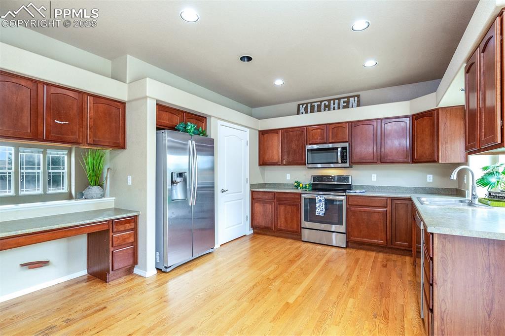 Kitchen featuring stainless steel appliances, light wood-type flooring, recessed lighting, light countertops, and brown cabinets