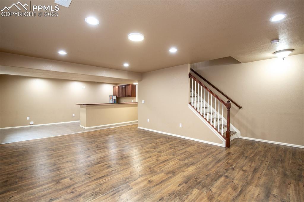Unfurnished living room with dark wood-style flooring, stairs, and recessed lighting