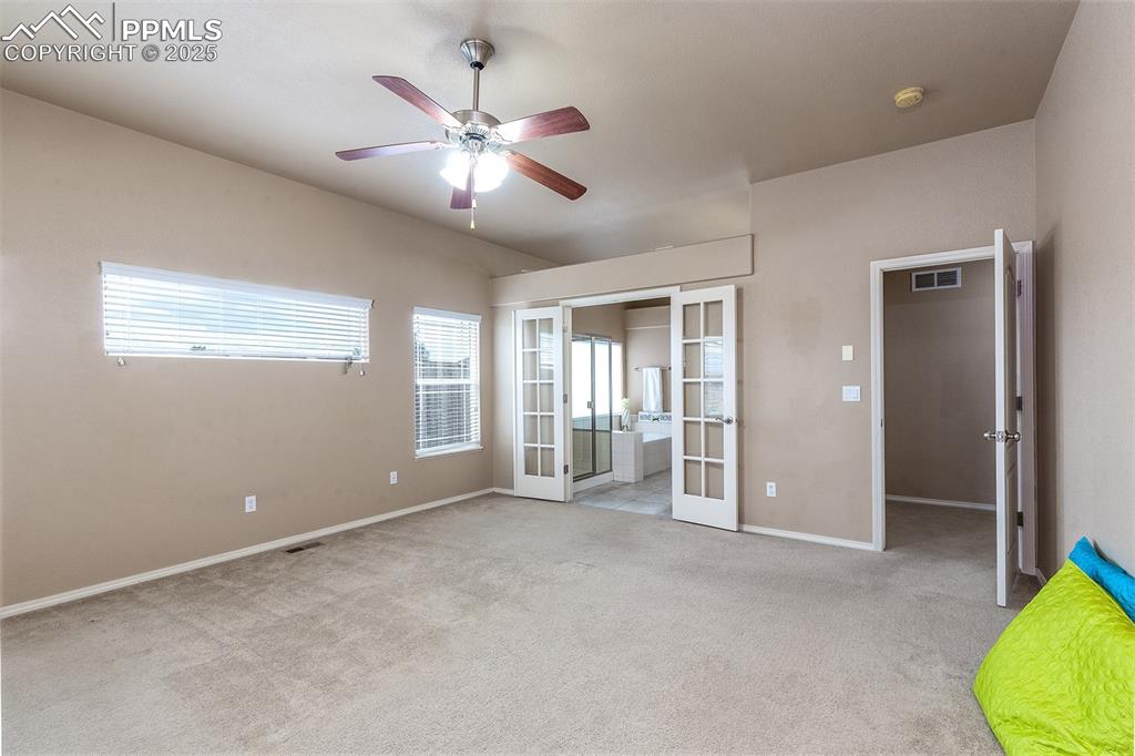 Unfurnished bedroom featuring french doors, carpet flooring, and a ceiling fan