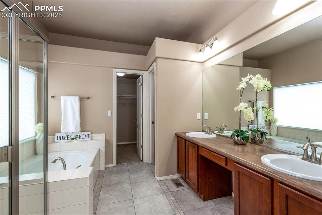 Bathroom with double vanity, a garden tub, tile patterned floors, and a walk in closet
