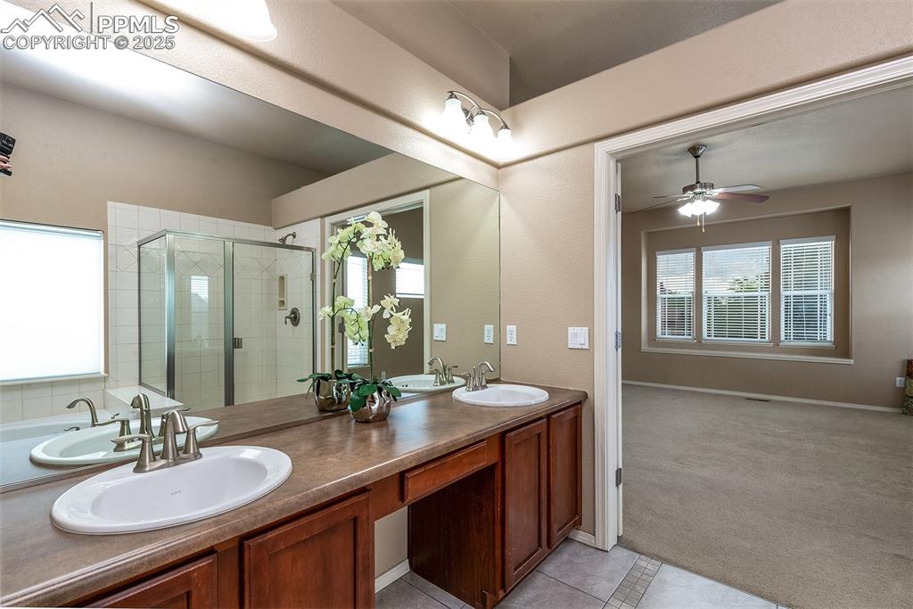 Full bath featuring a shower stall, double vanity, a ceiling fan, and tile patterned floors