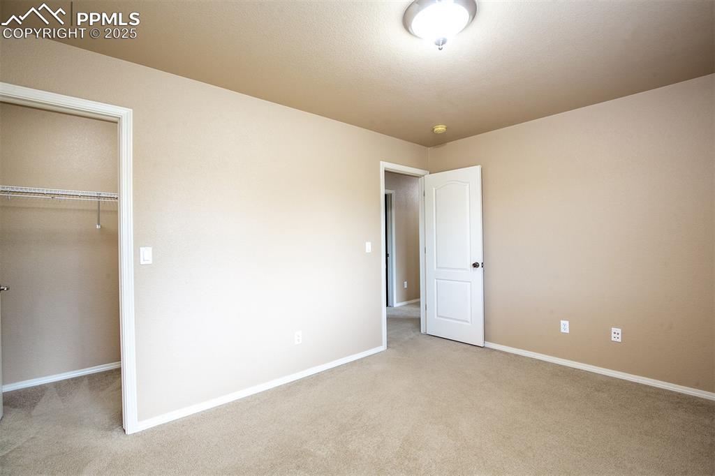 Unfurnished bedroom with light carpet and a spacious closet