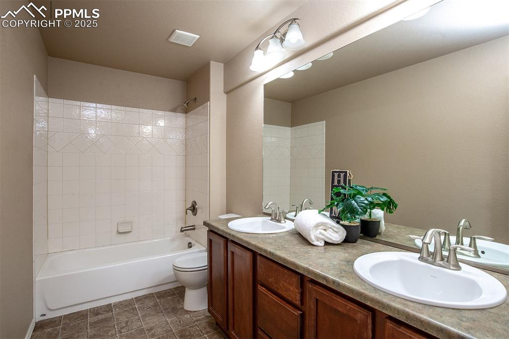 Full bathroom featuring double vanity and washtub / shower combination