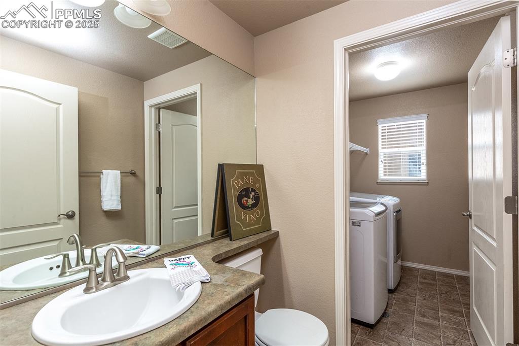 Bathroom with washing machine and clothes dryer and vanity