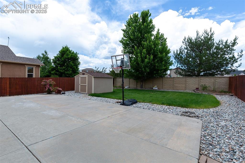 Fenced backyard featuring a storage shed and a patio area