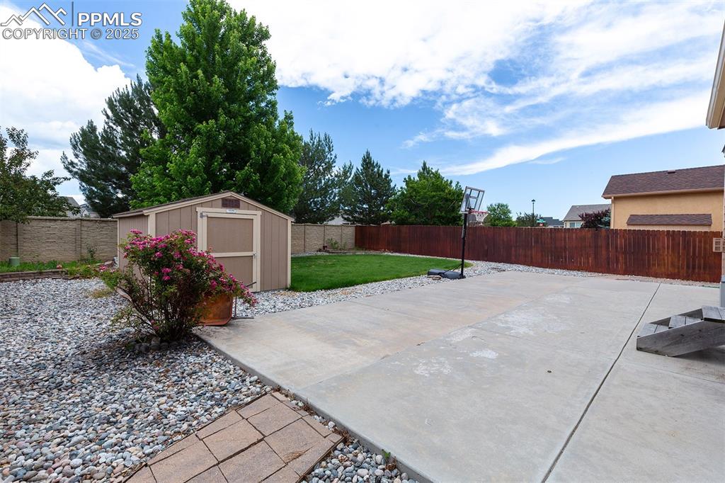 Fenced backyard featuring a shed and a patio